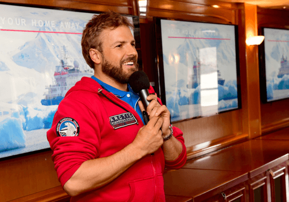 Expeditionsleiter der Kreuzfahrt begrüßt die Gäste in der Lounge